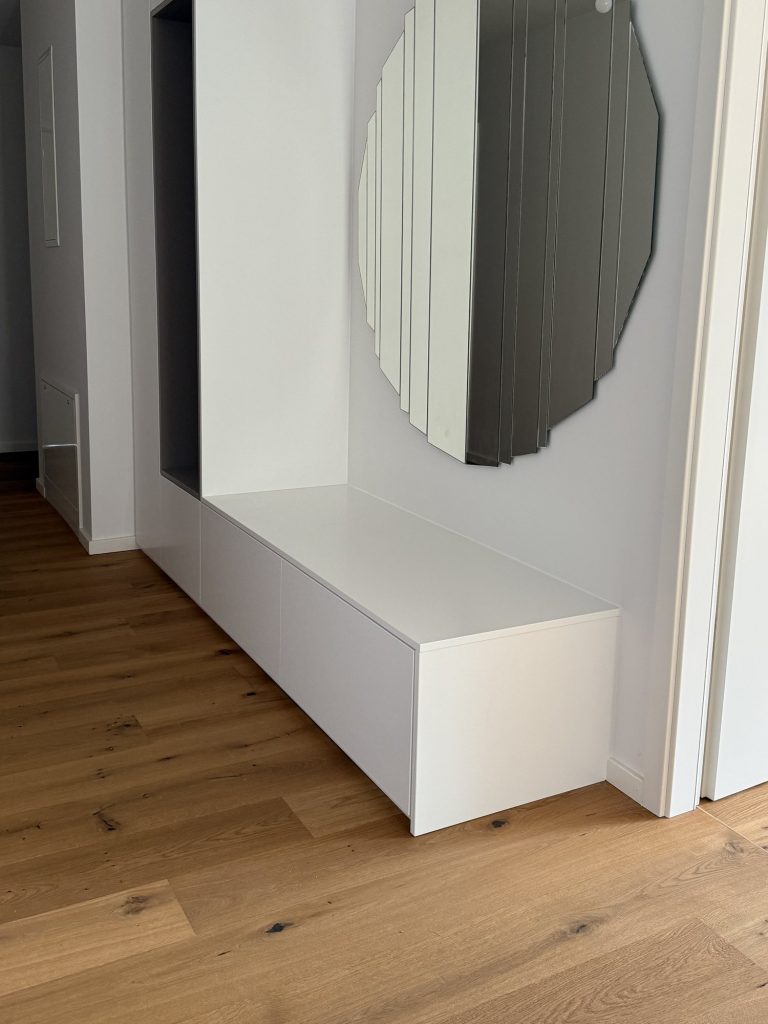 Weiße Garderobe mit Sitzbank und offener Nische