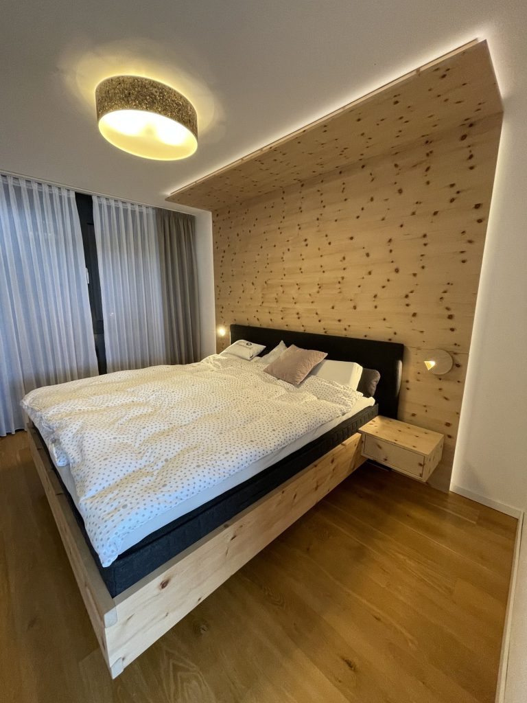 Schlafzimmer mit Wand aus Zirbe
